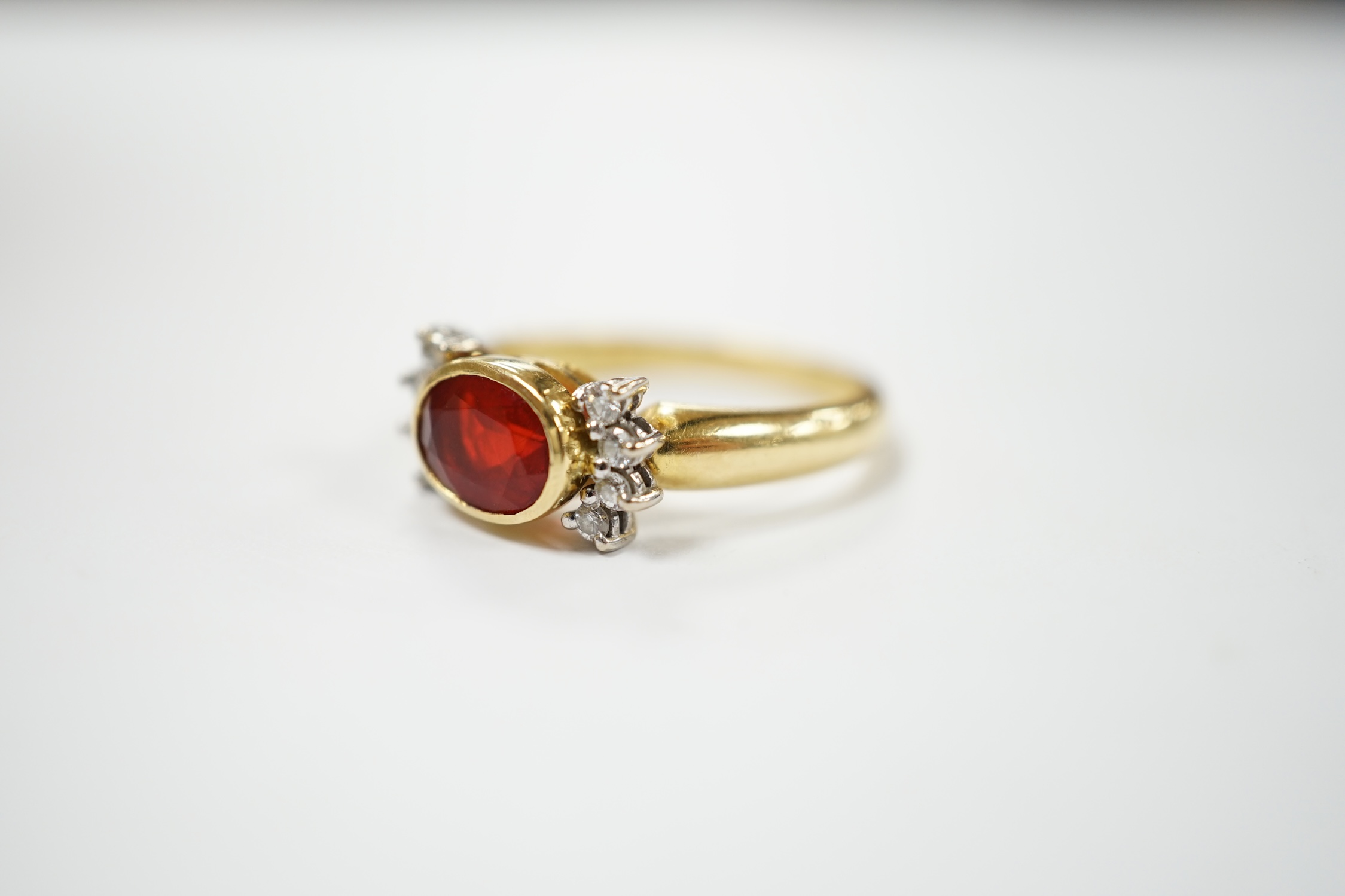 A modern 18ct gold, single stone fire opal? and eight stone diamond chip set dress ring, size L/M, gross weight 5.3 grams. Condition - fair to good